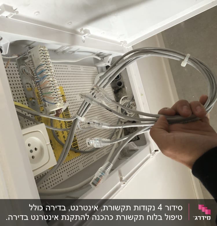 טכנאי מחזיק כבלים בארון תקשורת עם חיבורים